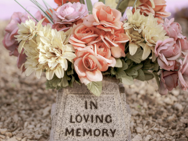 flowers on a grave with a marker saying 'in loving memory'